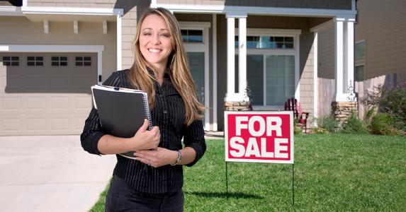 Successful woman real estate agent standing outside a home for sale highlighting local neighborhood SEO